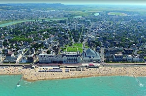 An aerial view of a coastal city with a large beach, a prominent building complex, and a river running through the city.