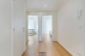 A hallway with wooden flooring and white walls, leading to two rooms with doors. - Seacarl - stunning apartment with frontal sea view (Nieuwpoort)