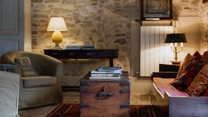 A cozy living room with a stone wall, a wooden chest, a sofa, a lamp, and a table. - Amazing villa with swimming pool into the nature with view over the Adriatic sea (Marche)
