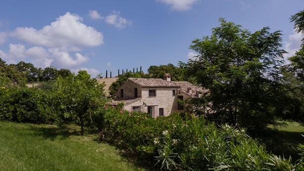 A stone house with a tiled roof surrounded by lush greenery and trees. - Amazing villa with swimming pool into the nature with view over the Adriatic sea (Marche)