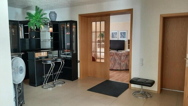 A modern kitchen with a black countertop, a fan, and a potted plant.