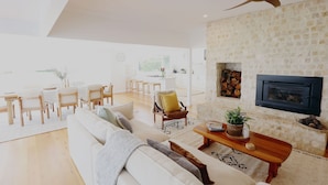 A spacious living room with a white sofa, wooden coffee table, and a fireplace. - Wrights Bay House★Sea View★Private Beach★Robe (Mount Benson)