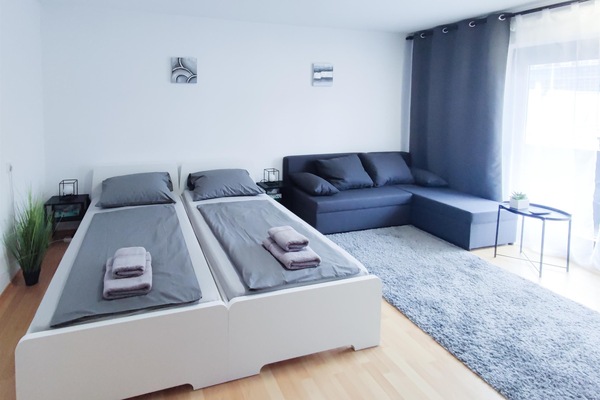 Schlafzimmer 1 mit Doppelbett, Schlafcouch und Smart-TV, Designerstuhl und Tisch