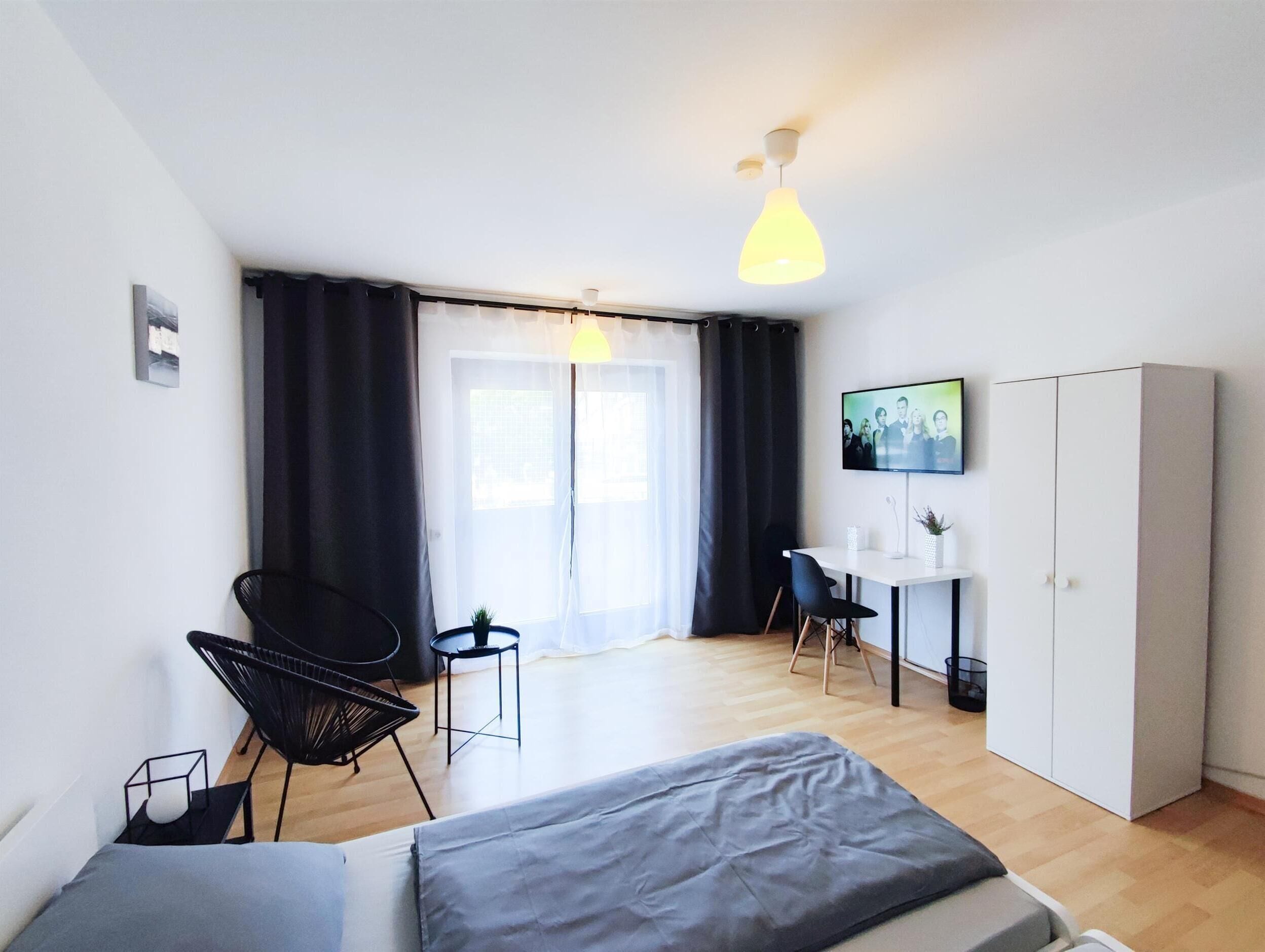 Ein modernes Hotelzimmer mit Bett, Schreibtisch, Stuhl und Kleiderschrank.