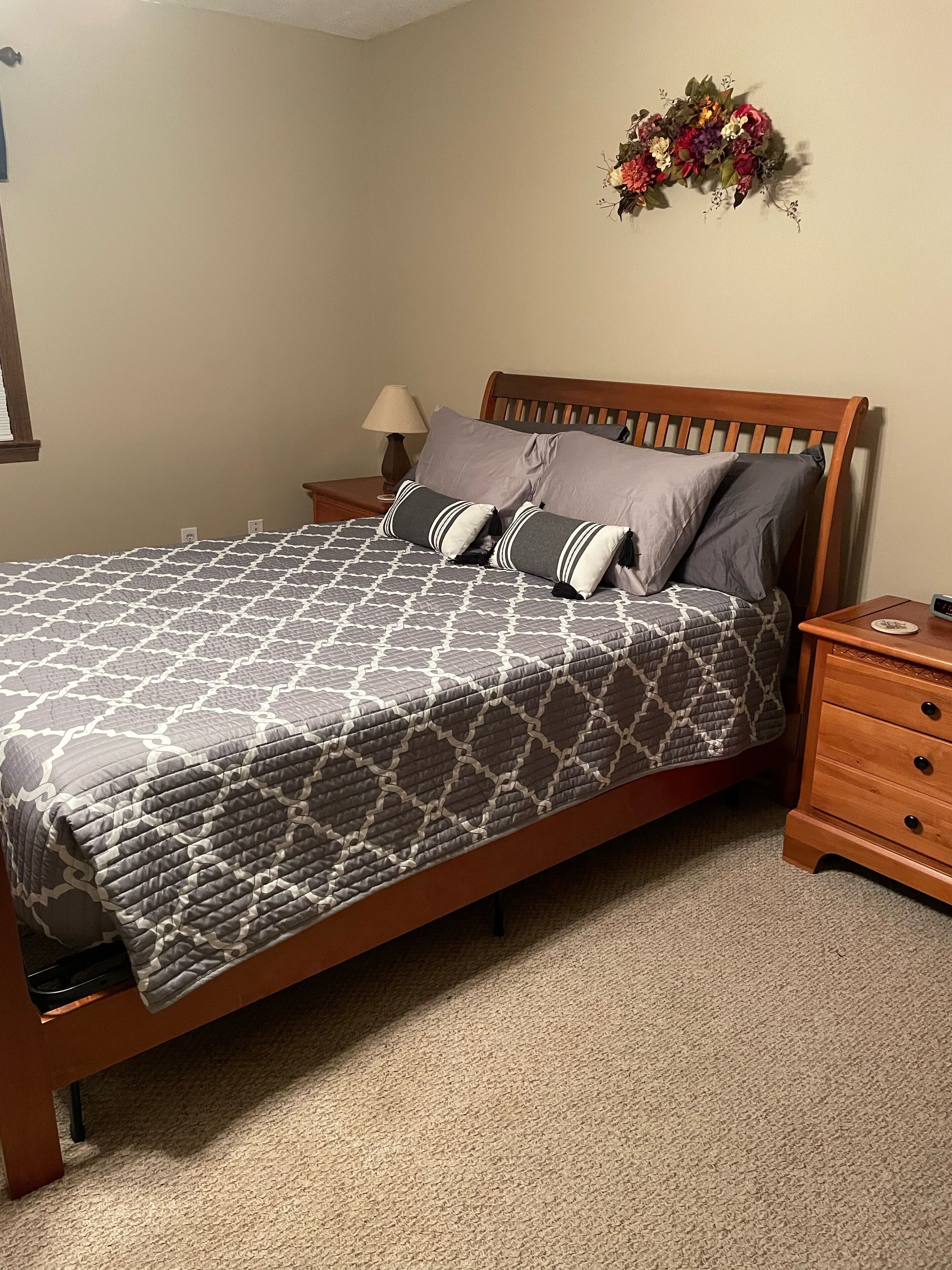 Una camera da letto con un letto, un comodino, una lampada e un elemento decorativo al muro.