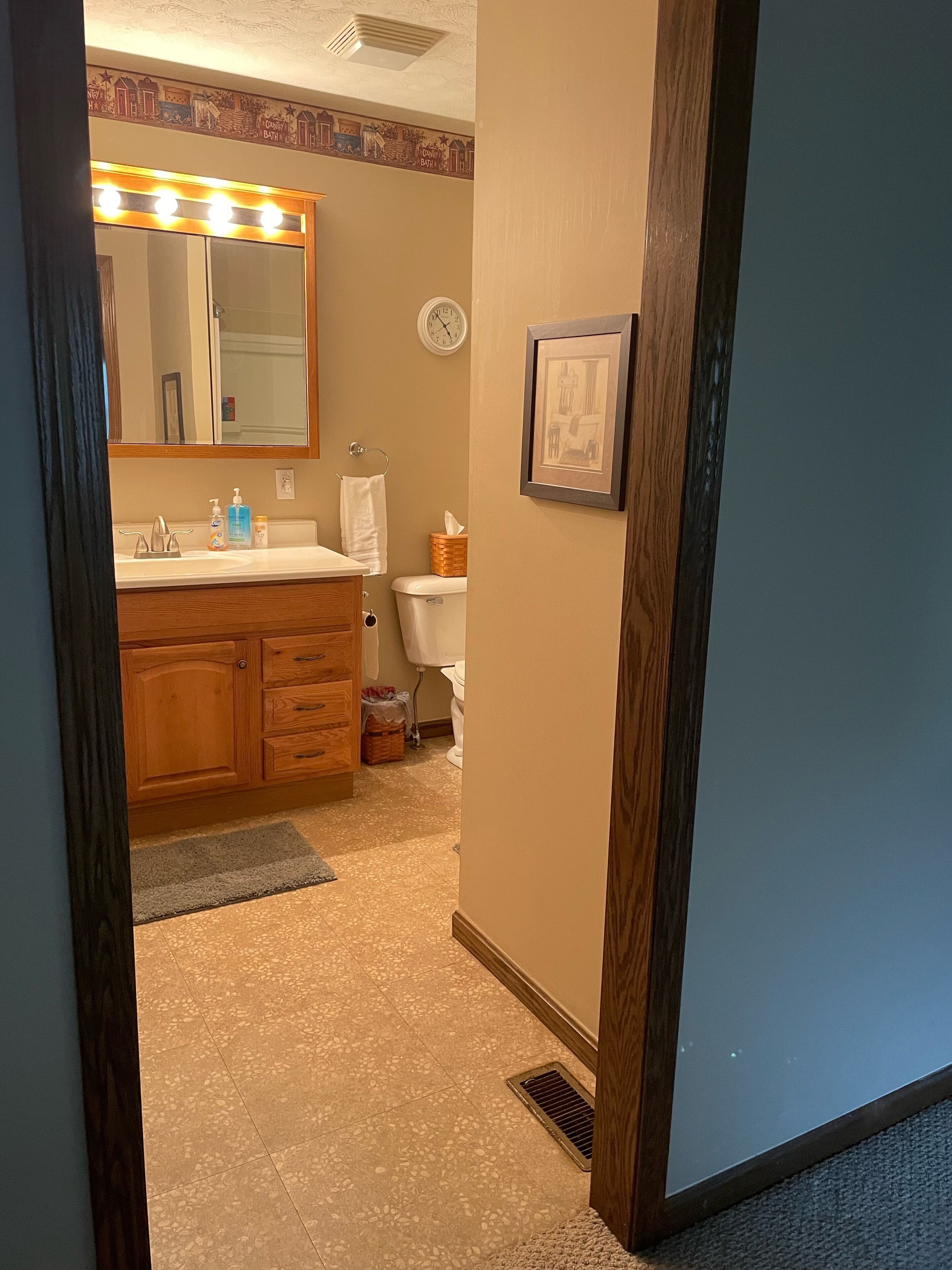 A bathroom with a vanity, sink, mirror, and toilet.