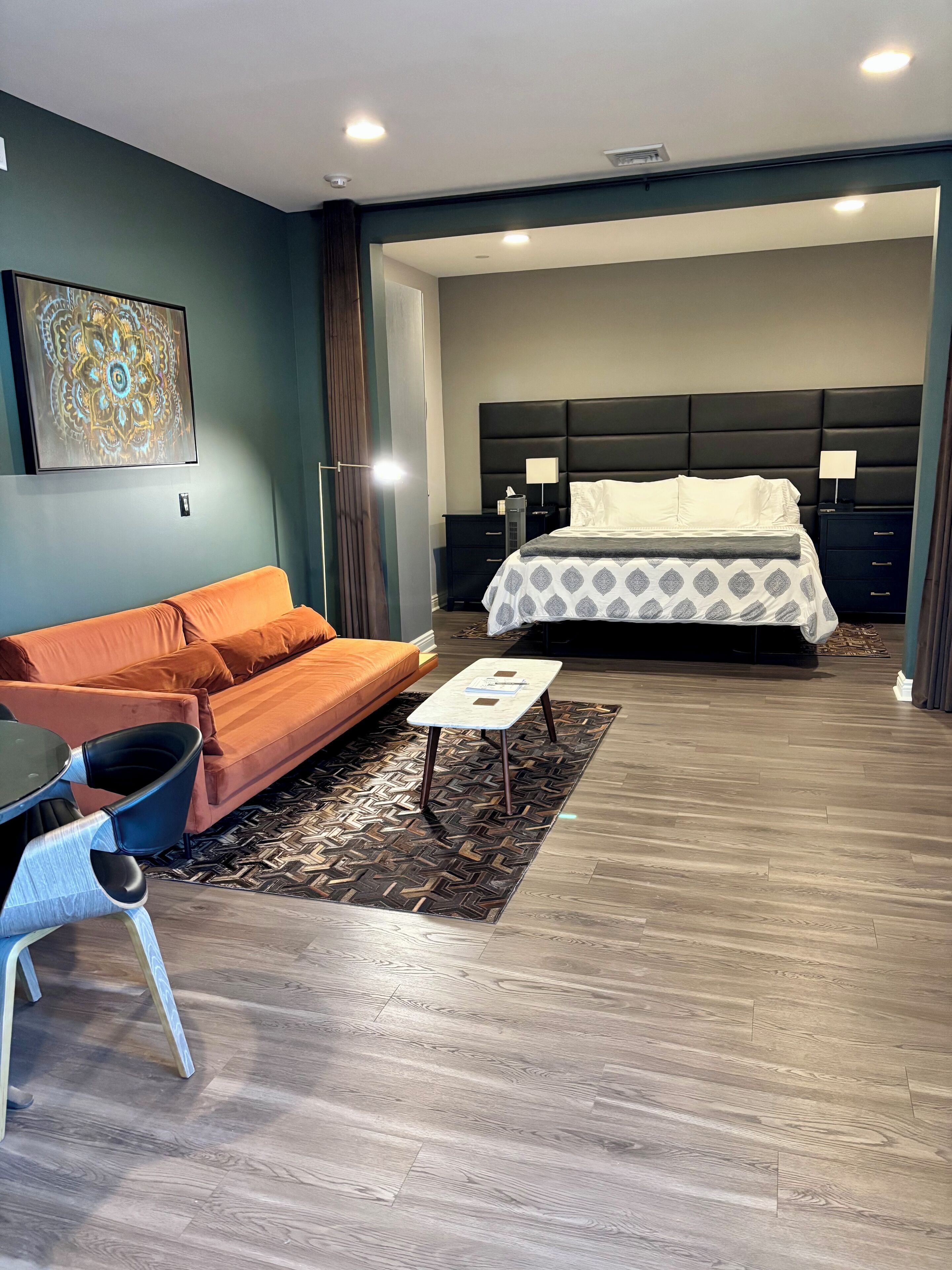 Une chambre d’hôtel moderne avec un grand lit, un canapé, une petite table et un tapis décoratif.