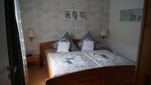 Quarto com cama de madeira, duas mesas de cabeceira e luminárias fixadas na parede.