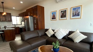 A modern living room with a brown leather sofa, a wooden coffee table with a plant, and a patterned rug. - Gringo-Gulch, 3 bedroom w/view, pool/patio (Puerto Vallarta)