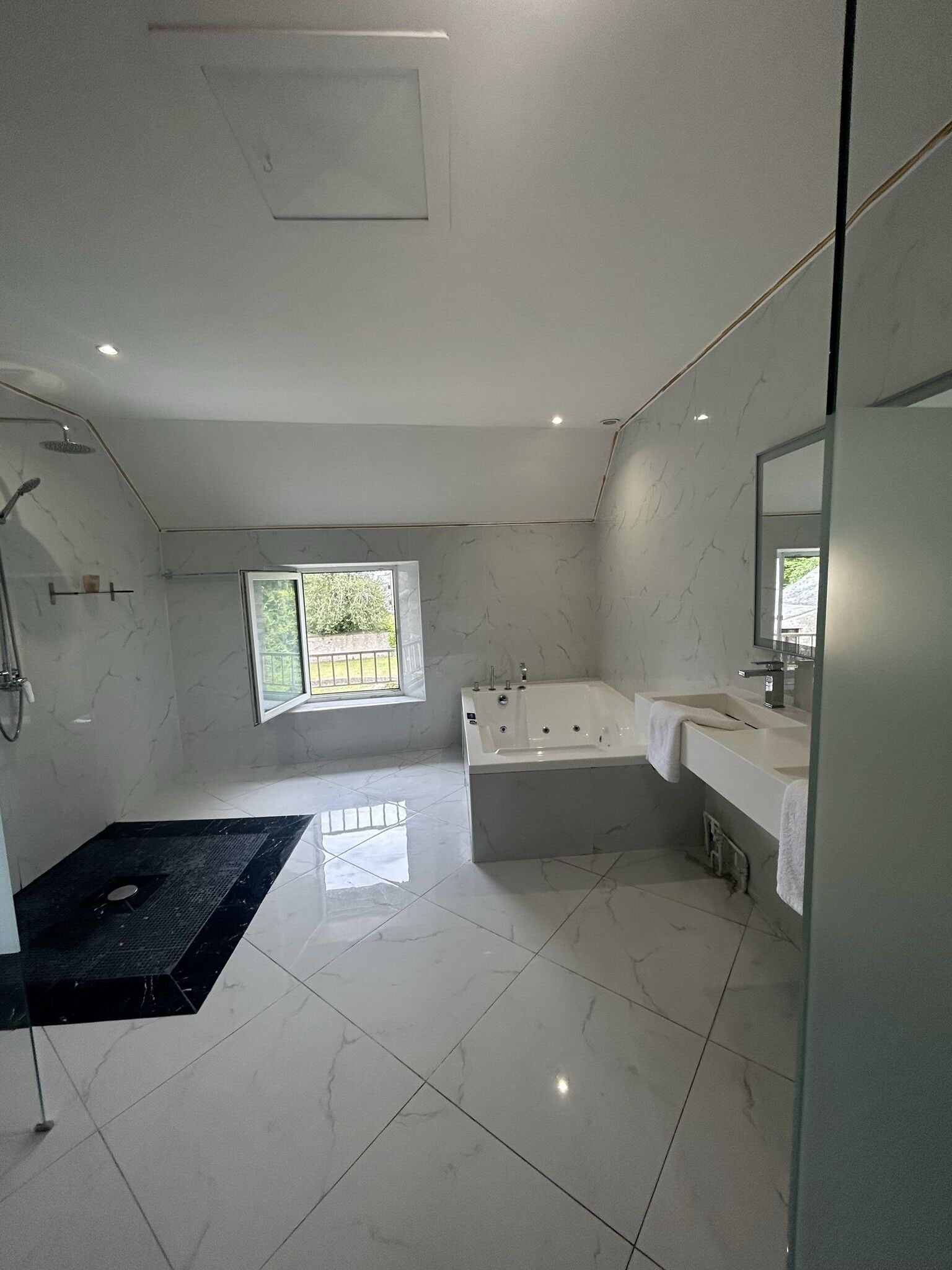 A modern bathroom with a large bathtub, a separate shower area, and a vanity with a mirror.