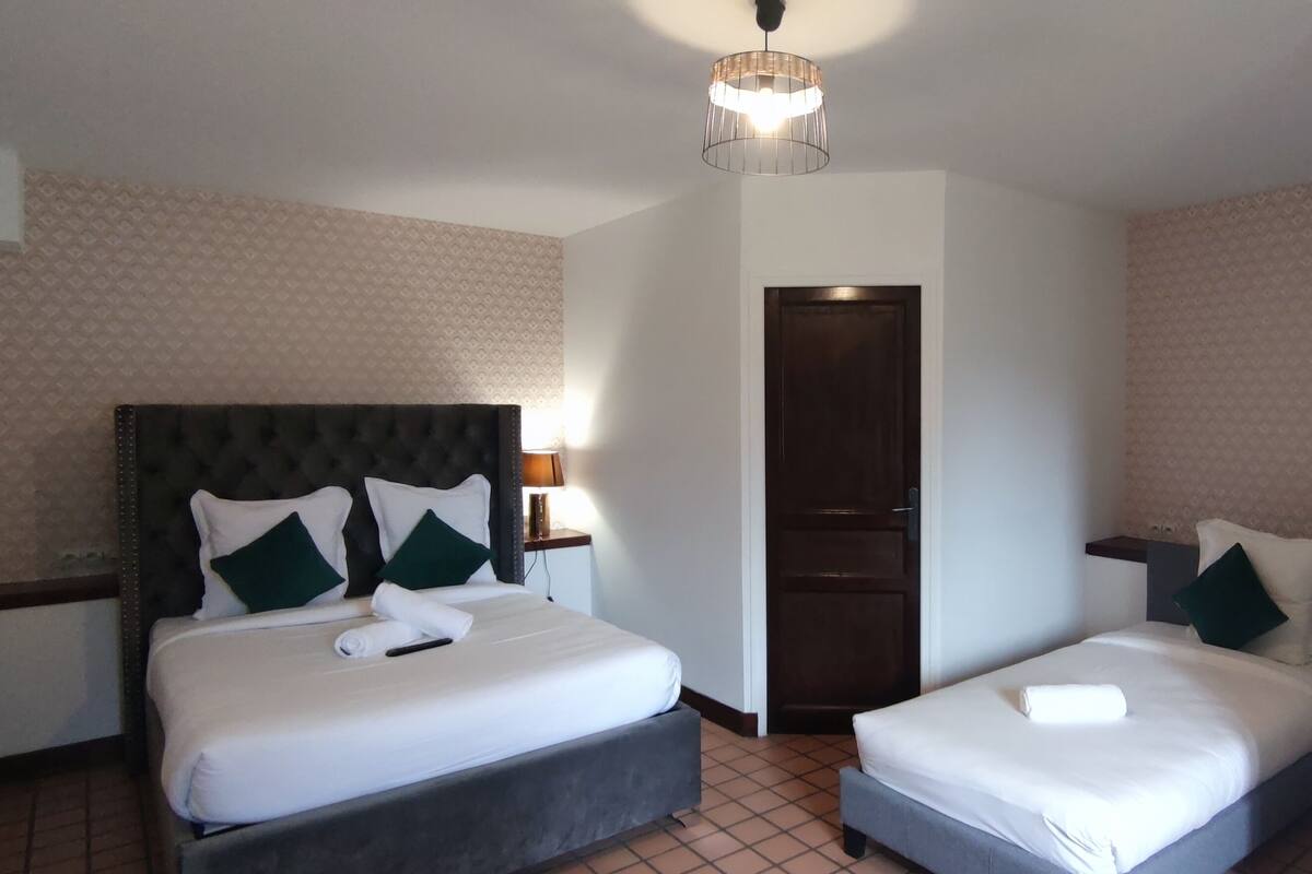 Habitación de hotel con dos camas, un armario, un espejo y una lámpara en el techo.