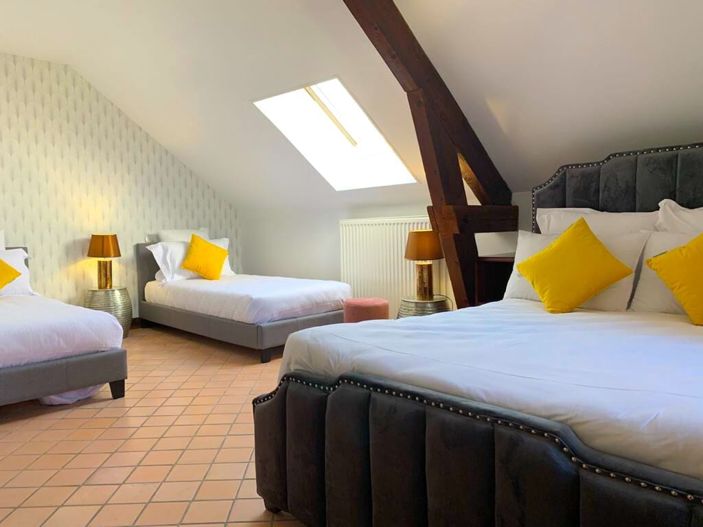 A hotel room with two beds, a skylight, and a radiator.
