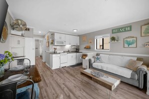 Une cuisine moderne avec des meubles blancs, un four à micro-ondes et un coin repas comprenant une table et des chaises en bois.