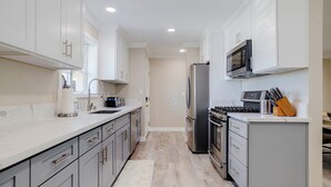 A modern kitchen with white cabinets, stainless steel appliances, and a marble countertop.