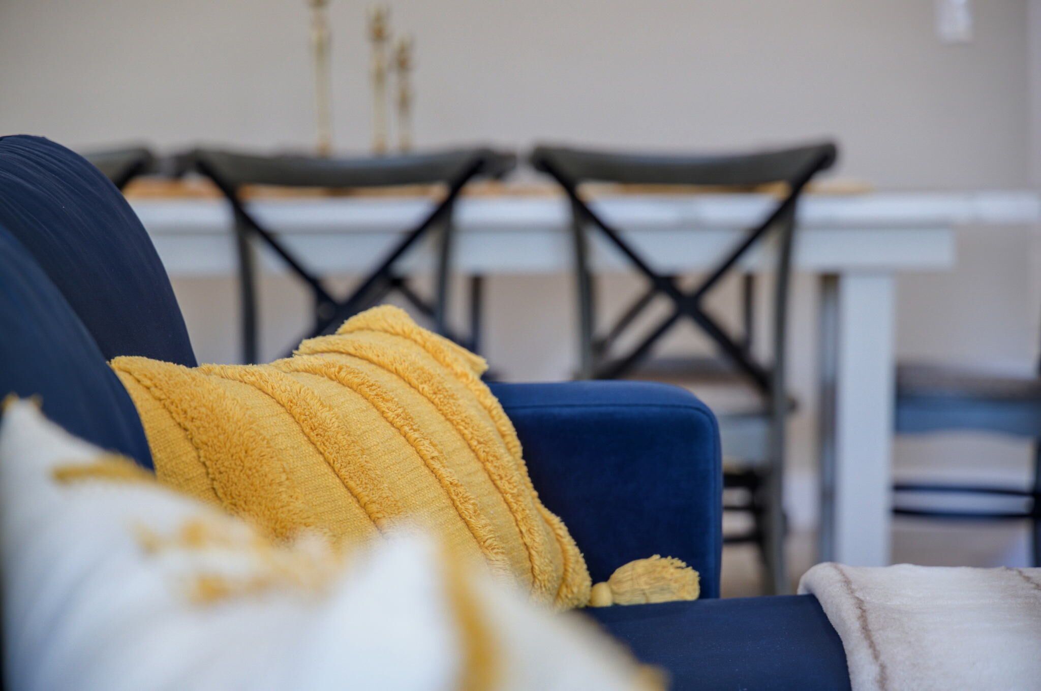 Una poltrona blu con un cuscino giallo e una coperta bianca.