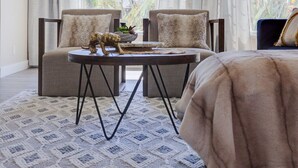 A cozy room with a high ceiling, two sofas with patterned cushions, a small round table, and a patterned rug.