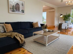 A modern living room with a dark blue sofa, a wooden coffee table, and a patterned rug. - BerwickHills Stylish 3 BdrmHome *Free Wifi*NetFlix (Berwick)