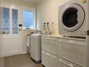 Un cuarto de lavandería con lavadora de carga frontal, secadora y un lavamanos.
