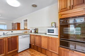 A modern kitchen with wooden cabinets, a dishwasher, a microwave, and a stainless steel oven. - BerwickHills Stylish 3 BdrmHome *Free Wifi*NetFlix (Berwick)