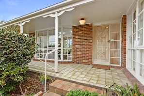 A house with a covered porch, a brick wall, and a decorative door.