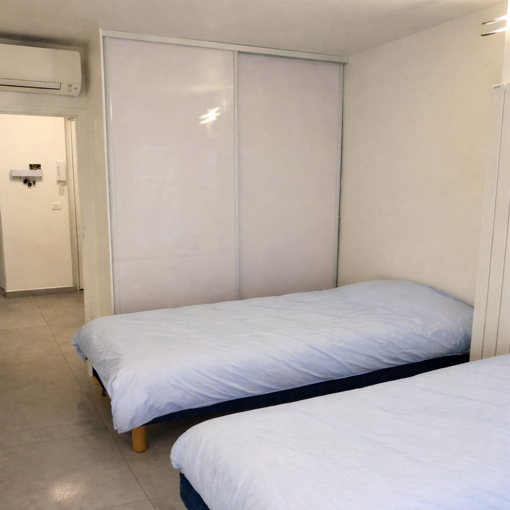 A bedroom with two single beds, a wardrobe, and a door leading to a bathroom.