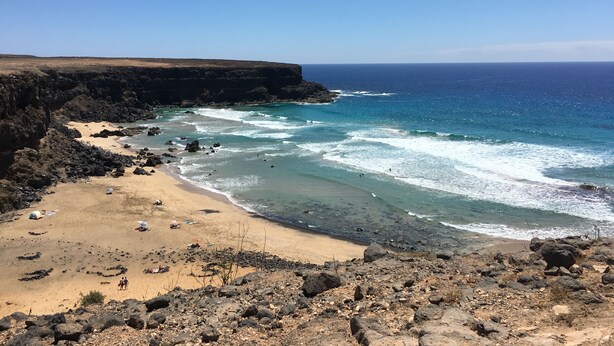 Eine Küstenlandschaft mit einem felsigen Strand, klarem, blauem Meer und einer Klippe, die auf den Ozean blickt.