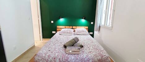 A single bed with a floral bedspread, a wooden headboard, and two wall-mounted lights.