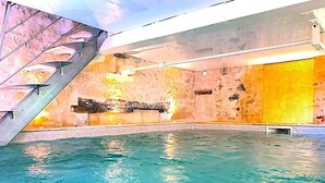 An indoor swimming pool with a modern design, featuring a central staircase and a textured wall. - DOMAINE DU MOULIN D'ANDRAUT Bordeaux-horses-golf-St Emilion (Saint-Sulpice-et-Cameyrac)