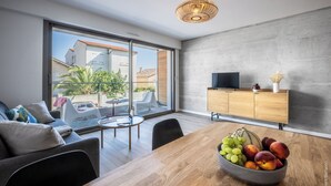 Een moderne woonkamer met een eettafel, bank en een televisie op een houten dressoir.