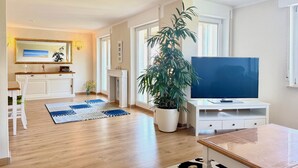 A spacious living room with a large TV, a fireplace, a potted plant, and a dining area. - Weinberg Idyll vacation apartment - Fantastic view over vineyards to Lake Constance (Lindau)
