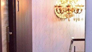 Un couloir avec un lustre, une porte et un escalier.