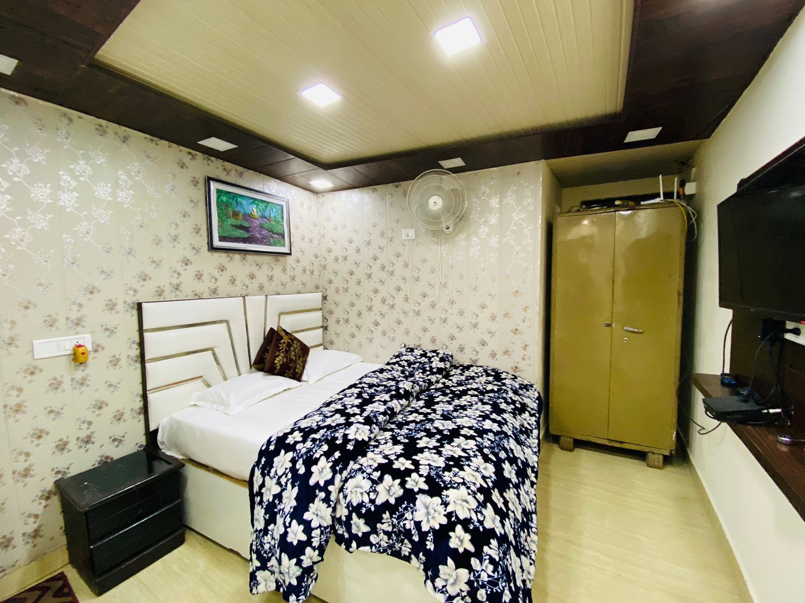 Ein Schlafzimmer mit einem Bett, einem Kleiderschrank, einem Fernseher und einem Deckenventilator.