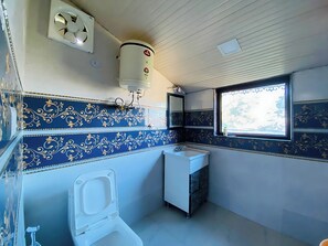A compact bathroom with a toilet, sink, and window. - Rudhraksh Villa 4BR Perfect vacay Villa (Mussoorie)