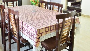 Un coin repas avec une table dressée pour six personnes, entourée de chaises en bois. Un vase décoratif rempli de fleurs est posé sur la table.