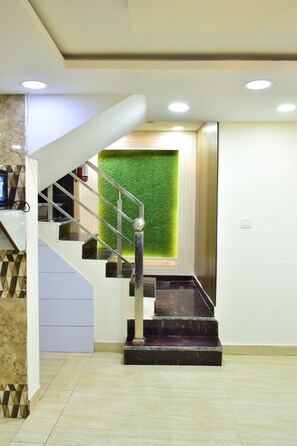 Un escalier moderne avec une rampe en verre et un mur vert en haut.