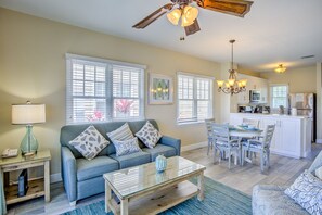 A living room with a sofa, coffee table, and a dining area with chairs and a table.