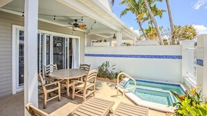 A covered patio with a pool, wooden furniture, and palm trees. - Waterfront Retreat  (Duck Key)