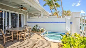 A poolside area with a dining table and chairs, a pool, and palm trees. - Waterfront Retreat  (Duck Key)