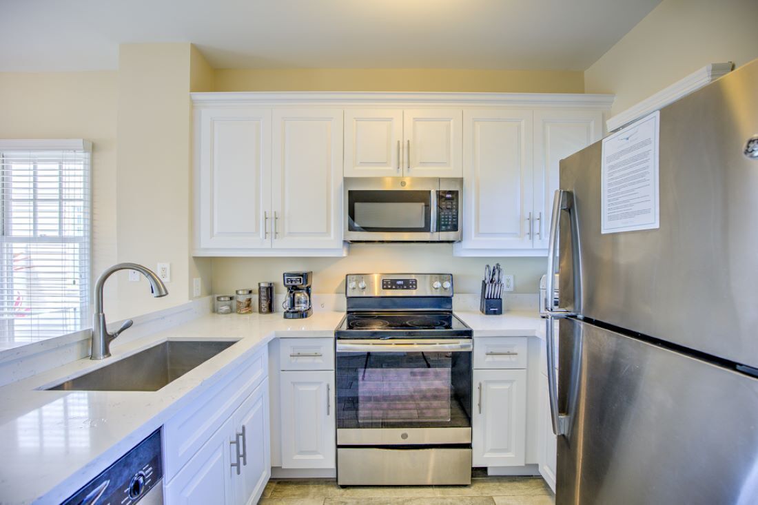 A modern kitchen with white cabinets, stainless steel appliances, a double sink, and a built-in oven.