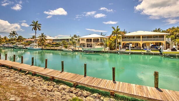 A marina with boats docked, a wooden dock, and a building with a covered area. - Waterfront Retreat  (Duck Key)