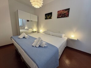 A hotel room with a large bed, a mirror, two wall-mounted lights, and two framed pictures.