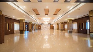 Un amplio vestíbulo de hotel con piso de mármol pulido, paneles de madera y un candelabro central.