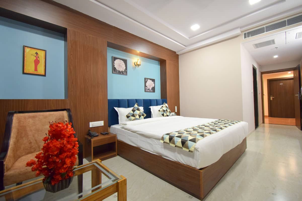 Une chambre d’hôtel avec un lit, une table de chevet, une chaise et un vase de fleurs.