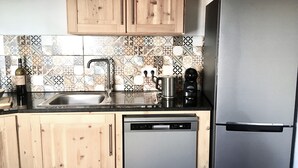 Una cucina con mobili in legno, un lavandino in acciaio inox, una macchina da caffè e un frigorifero.