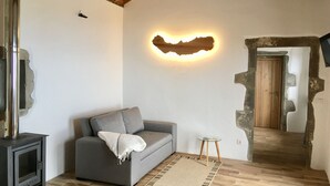 Un accogliente soggiorno con un divano grigio, un tavolino, un caminetto e una parete in pietra rustica.