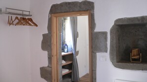 Una stanza con parete in pietra, porta in legno, uno scaffale con asciugamani e un appendiabiti.