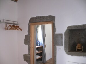 A room with a stone wall, a wooden door, a shelf with towels, and a hanging rack. - Vacation home with fantastic sea views and whirlpool (Pedreira, Nordeste)