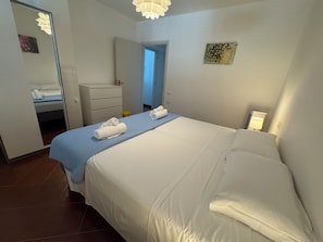 A hotel room with a bed, a dresser, a mirror, and a door leading to another room.