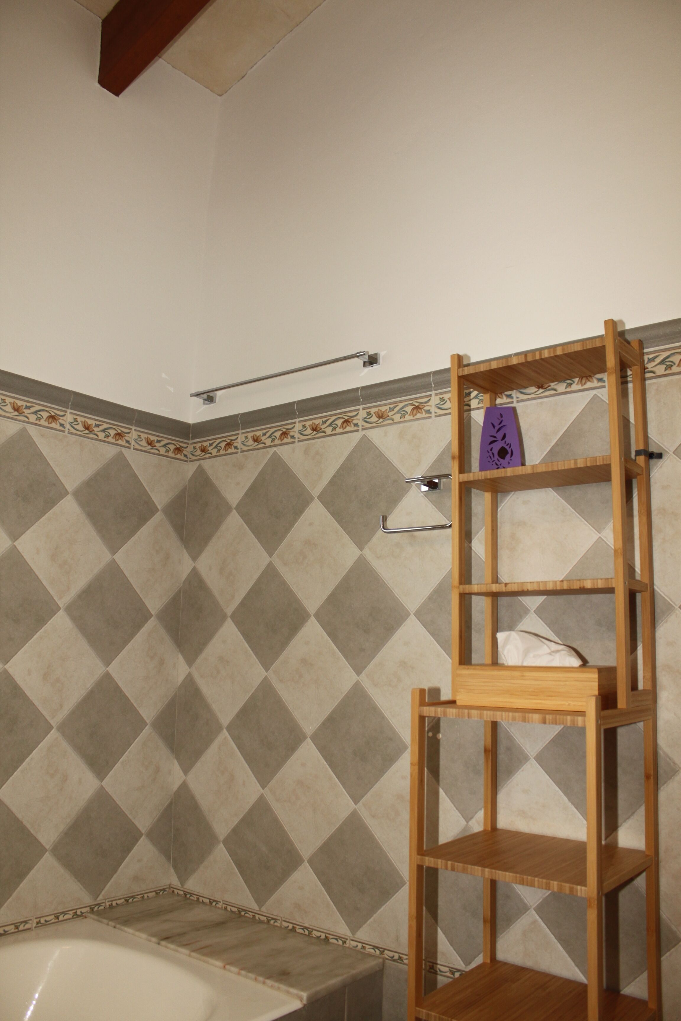 Een badkamer met een houten plank, een handdoekhouder en een behangen muur.