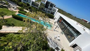 A modern building with a swimming pool, surrounded by greenery and a clear sky. - Cozy loft with private jacuzzi. (Mérida)